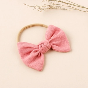 Pink waffle texture baby bow headband with high-stretch nylon band on minimalist background