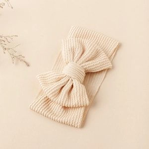 Gros plan du bandeau bébé beige en tricot côtelé avec un grand nœud texturé