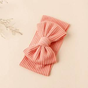 Gros plan du bandeau bébé rose avec nœud côtelé et texture ondulée douce