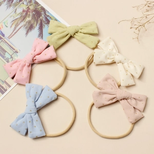 Détail de cinq bandeaux bébé en velours côtelé avec pois dorés sur bandes nylon