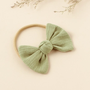 Close-up of soft light green cotton linen bow on high elasticity nylon baby headband