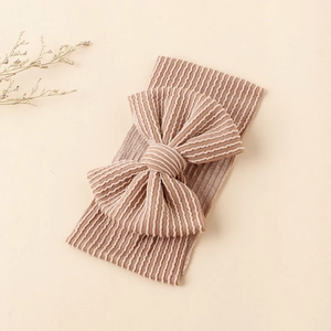 Détail du bandeau bébé en maille côtelée marron clair avec un grand nœud texturé