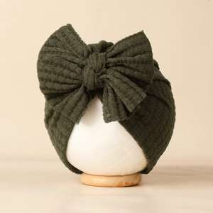 Détails de la texture du bonnet bébé vert olive en maille gaufrée avec un grand nœud doux