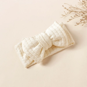 Detailed view of cream waffle knit baby headband with a large soft decorative bow