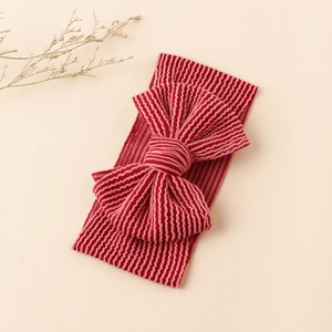 Détail d'un bandeau bébé en tissu côtelé rouge avec un grand nœud décoratif 3D