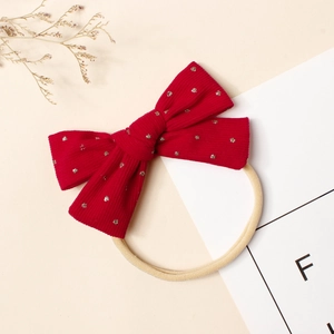 Détail du nœud en velours côtelé rouge à pois dorés sur bandeau élastique en nylon