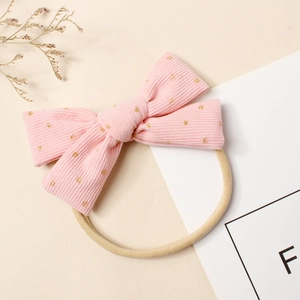 Détail du nœud en velours côtelé rose avec paillettes dorées sur bandeau en nylon