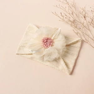 Detail of baby nylon headband with knit texture, mesh flower and satin ribbon bow