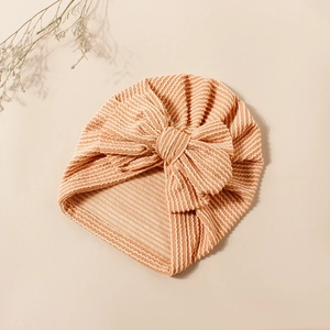 Detailed close-up of orange and white striped baby turban with large decorative bow