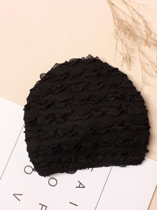 Dettaglio di un turbante nero per neonati con balze plissettate su sfondo minimalista
