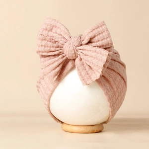 Détail du bonnet gaufré rose pour bébé avec un grand nœud en tissu côtelé