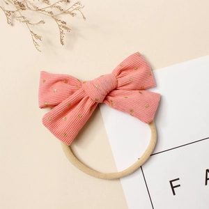 Détail d'un bandeau en velours côtelé rose avec pois dorés sur bande en nylon
