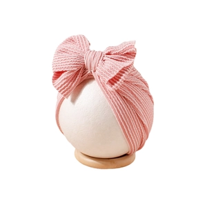 Pink ribbed striped baby turban hat with bow decoration on a white head model