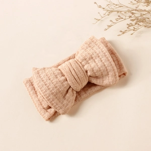 Detailed view of nude waffle knit baby headband featuring a large double-layered bow
