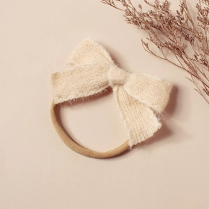 Détail du nœud en tricot pelucheux crème sur un bandeau élastique en nylon souple