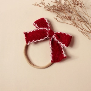 Détail du bandeau bébé avec nœud tricoté rouge, bordure pelucheuse et bande élastique douce