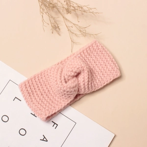 Détail d'un bandeau en tricot rose avec un design de nœud croisé doux et texture laine