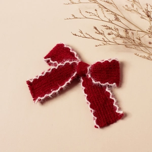 Dettaglio del fiocco in maglia rosso scuro con bordo in peluche bianco per bambine