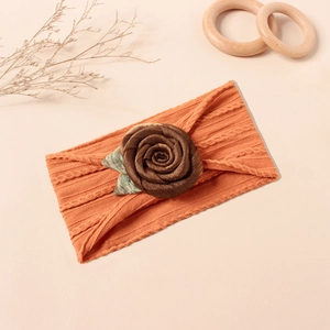 Details eines weichen, orangefarbenen Baby-Stirnbands mit handgefertigter brauner Stoffrose