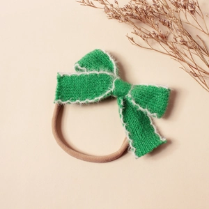 Détails de la texture tricotée du bandeau bébé vert avec bordure en fourrure et bande élastique