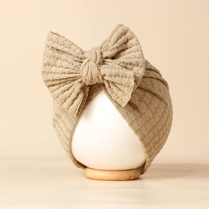 Détail du tricot gaufré kaki et du grand nœud sur ce bonnet turban pour bébé