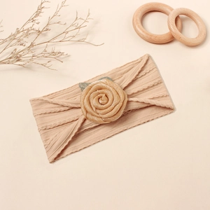 Detail eines Baby-Stirnbands aus Jacquard-Nylon mit Stoffrose und grünen Blättern
