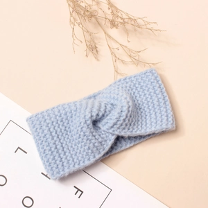 Détail d'un bandeau en tricot bleu clair avec torsion centrale et texture en laine