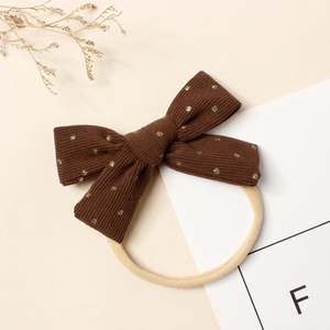 Détail du nœud en velours côtelé marron à pois dorés avec bandeau élastique beige