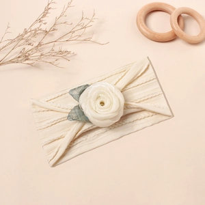 Detail eines Baby Stirnbands mit weißer Netzrose und Blättern auf Rippstrick