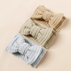 Three waffle knit baby headbands with large bows in blue, beige, and khaki colors