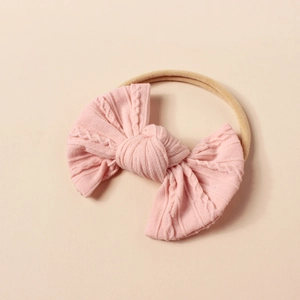 Detail einer rosa gestrickten Jacquard-Schleife auf elastischem Baby-Stirnband