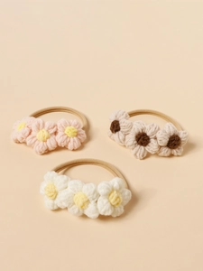 Dettaglio di fasce per capelli con fiori in maglia fatti a mano in rosa e beige