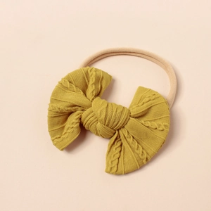 Makro-Detail von senfgelber Strickschleife auf weichem, dehnbarem Nylon-Baby-Stirnband
