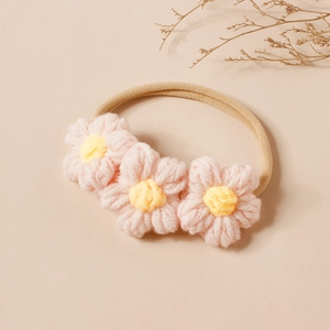 Dettaglio fascia per neonati con tre fiori in maglia fatti a mano rosa e gialli su elastico