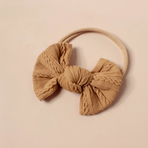 Detail von weicher Jacquard-Schleife am kamelfarbenen Baby-Stirnband für Neugeborene