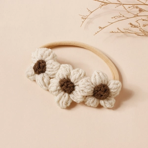 Dettaglio di tre fiori all'uncinetto su una morbida fascia elastica in nylon per neonati