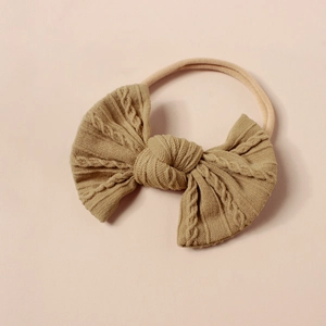 Detail eines kamelfarbenen Strick-Haarbands mit Zopfmuster und elastischem Nylon-Stirnband