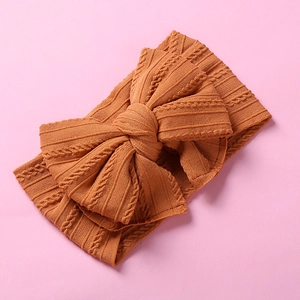 Détail d'un bandeau en nylon caramel avec un grand nœud tricoté et une texture côtelée