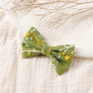 Détail d'une pince à cheveux en lin vert fait main avec broderies de fleurs jaunes