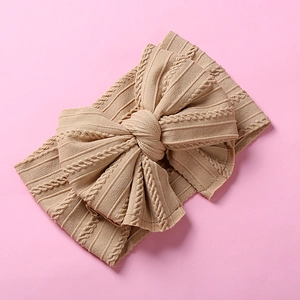Gros plan du bandeau bébé en nylon avec grand nœud jacquard en tricot beige doux