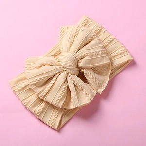 Détail du bandeau pour bébé en maille beige douce avec un grand nœud décoratif