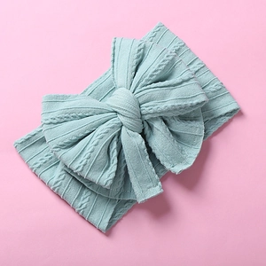 Détail de maille et grand nœud sur bandeau souple pour bébé en nylon vert menthe