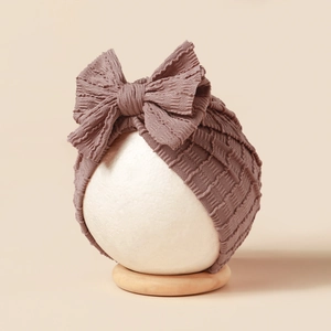 Dusty pink baby turban hat with a large bow detail made of elastic ribbed knit fabric
