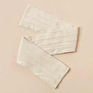 Detailed cable knit texture of a soft cream baby headband in a minimalist flat lay style