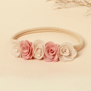 Détail de cinq fleurs de rose en tissu doux sur un bandeau bébé en nylon souple