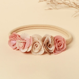 Gros plan de roses en tissu sur un bandeau extensible en nylon doux pour bébé fille