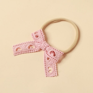 Dettaglio della fascia rosa in pizzo con fiocco e motivi a cuore per neonati e bambini