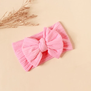Detail of pink cable knit baby headband with a large bow showing soft texture and high elasticity