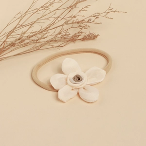 Détail d'une fleur en dentelle faite main et d'un bandeau élastique en nylon pour bébé