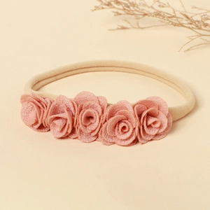 Détail de cinq roses en tissu faites main sur un bandeau élastique en nylon pour bébé